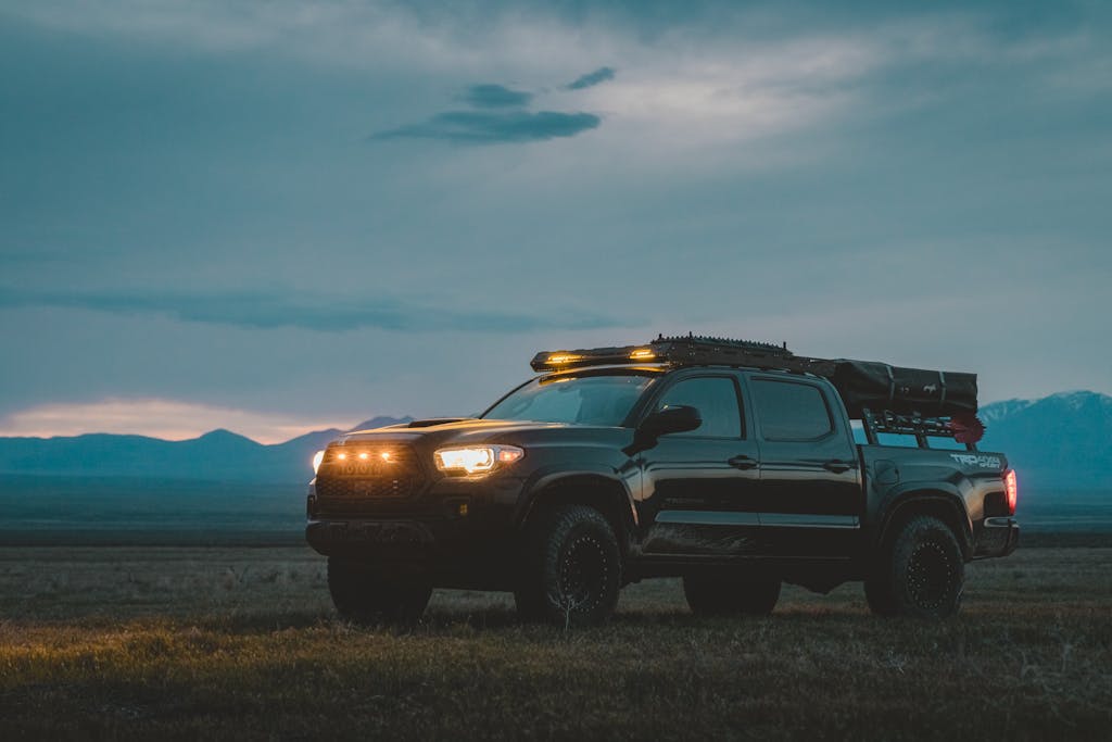 A black 4x4 pickup truck with headlights on in a foggy landscape at dawn. Adventure awaits.